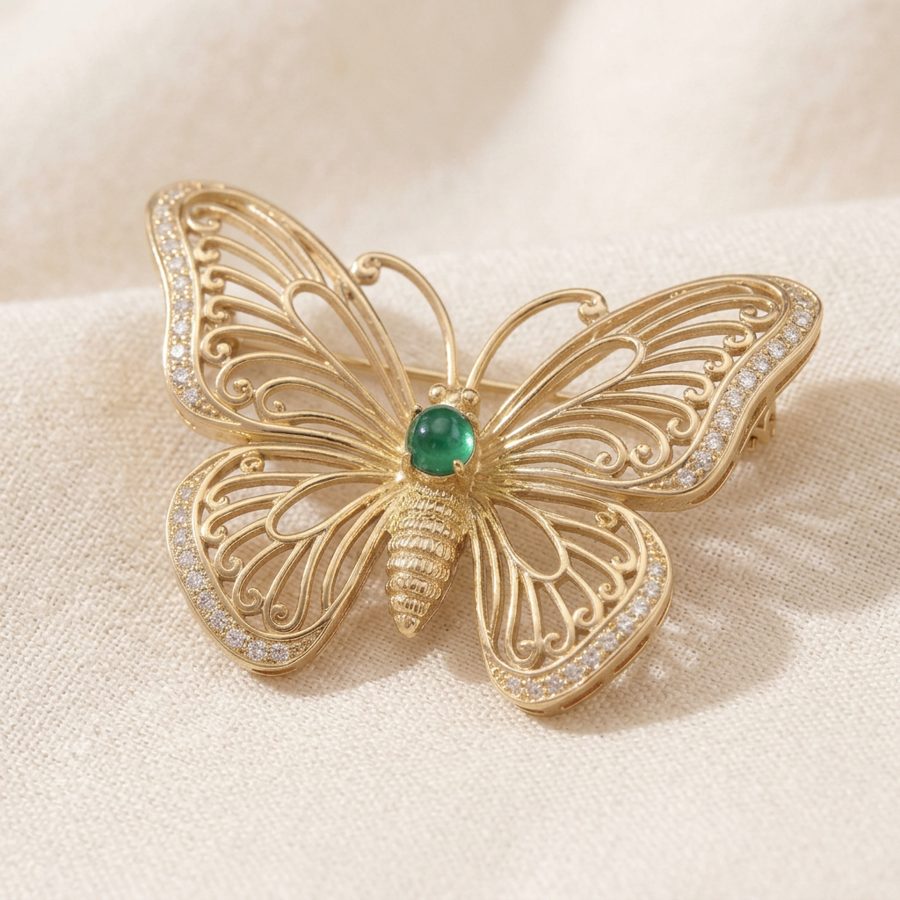Broche mariposa en filigrana dorada con piedra verde y cristales