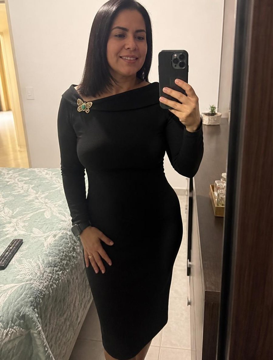 Clienta con el vestido midi negro frente al espejo de su casa